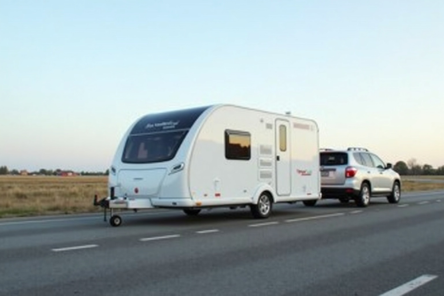 Wohnwagen angekuppelt an einen PKW auf einem Campingplatz